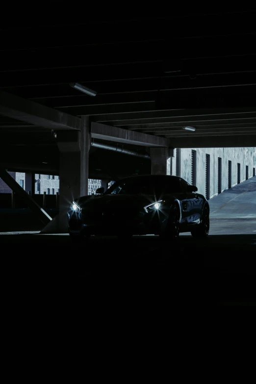 a black car parked under an overpass in the dark