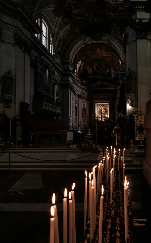 a row of candles sit in the church aisle