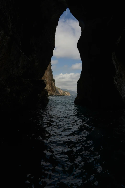 an arch on the side of a rock formation in a body of water