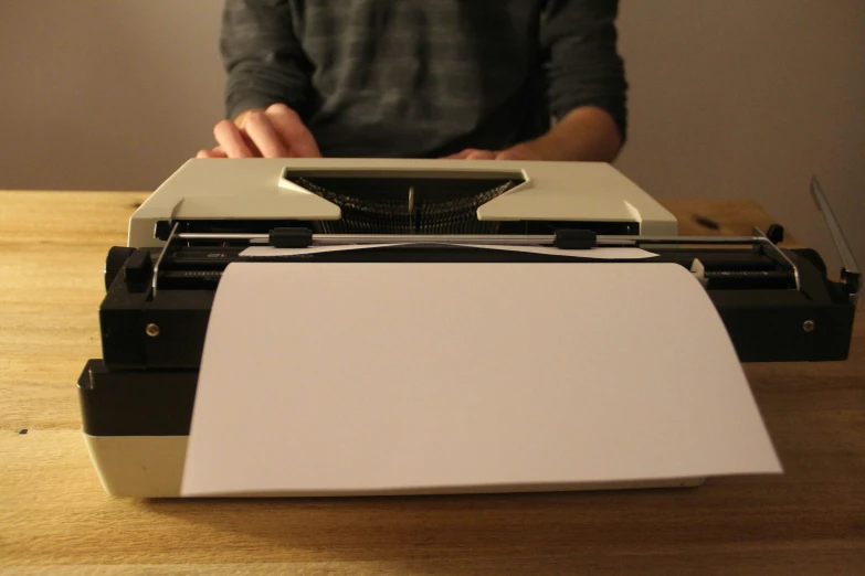 a man standing behind an old fashioned typewriter