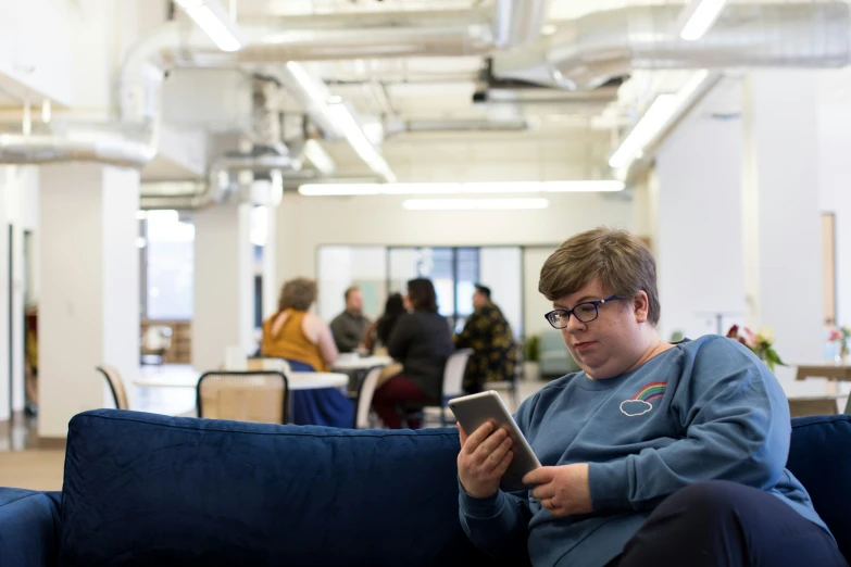 a man sitting on the couch reading soing in front of him