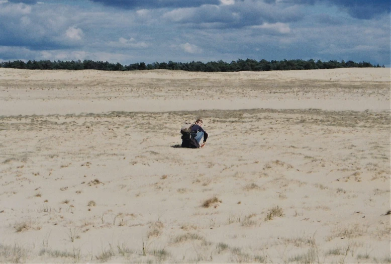 two people are sitting in the middle of a beach field