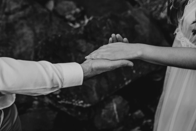 a bride and groom holding hands while standing near a tree