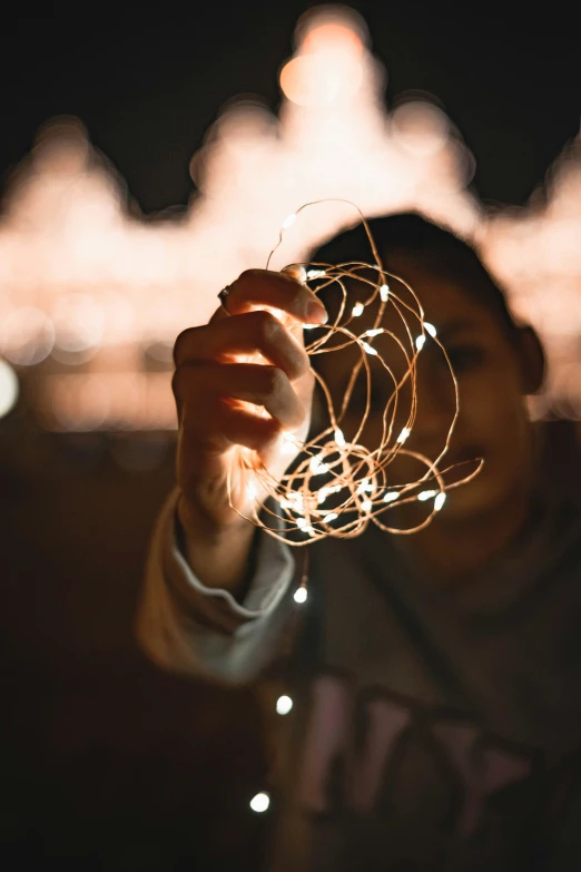 a man holds a string of string lights up to show the effect of stringing