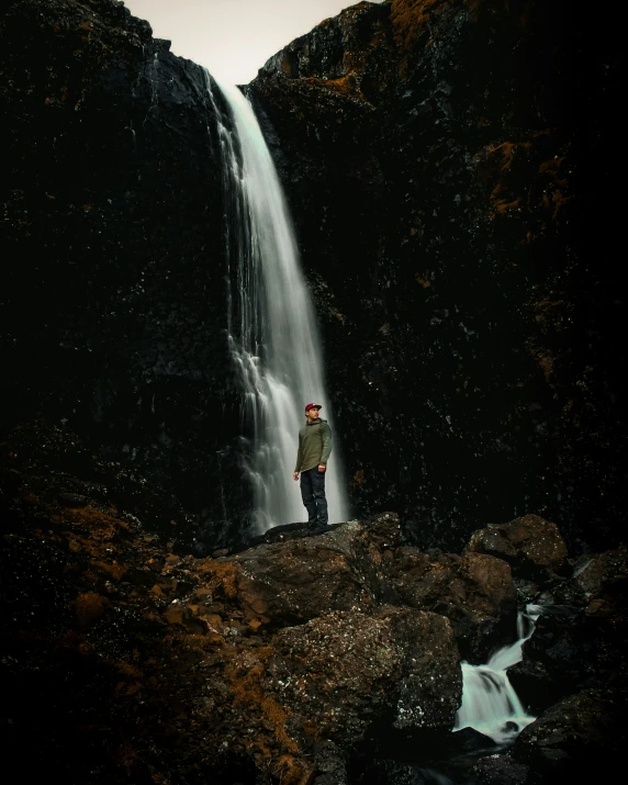 a man standing in front of a waterfall