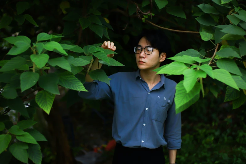 a person with glasses standing next to tree