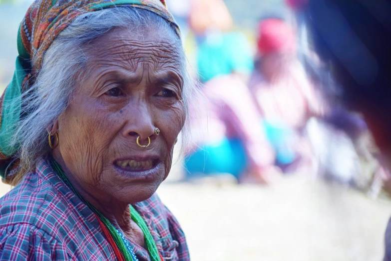 an old woman wearing a ring, looks at someone