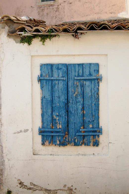 a blue window on a white stucco wall