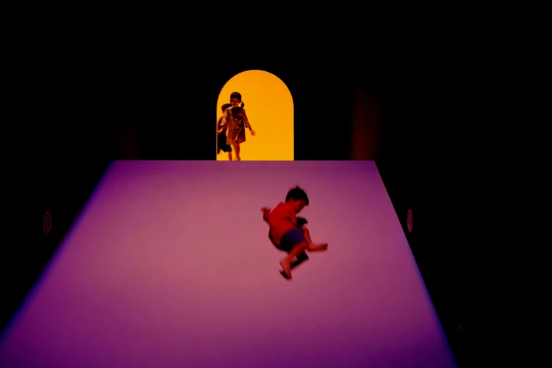 a person is jumping in the air with purple lit room