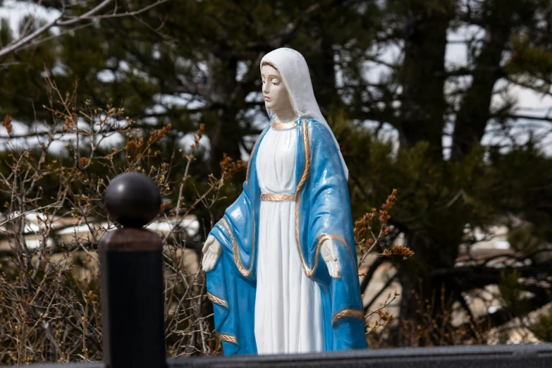 a blue statue of the mary mary statue next to a black pole