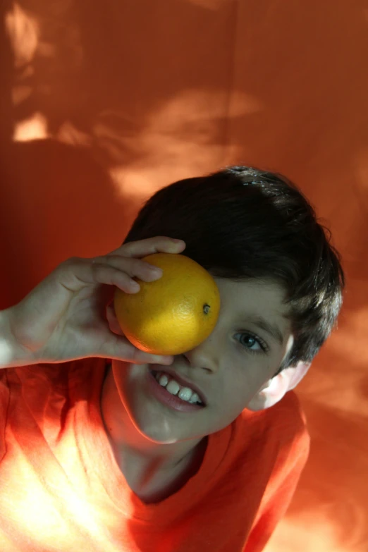 a  holds an orange and poses for the camera