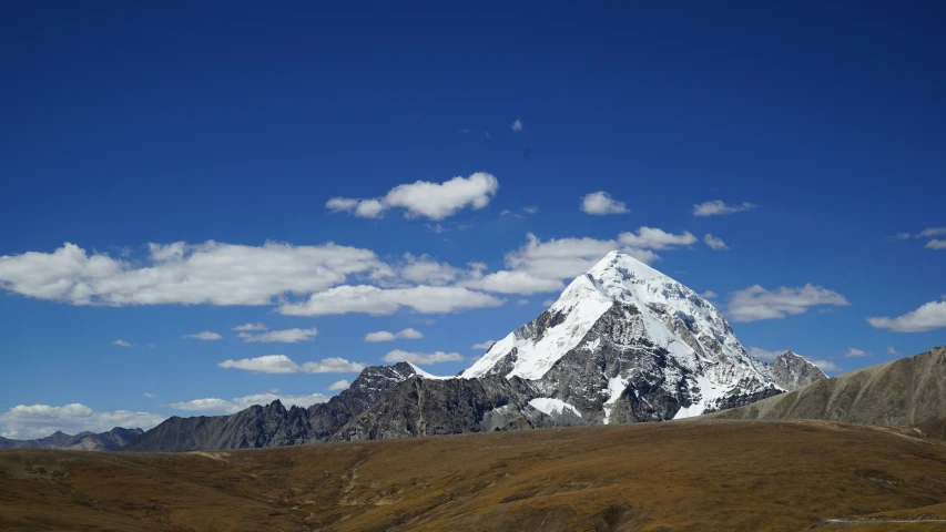 the mountain tops are in the foreground with white fluffy clouds and blue sky