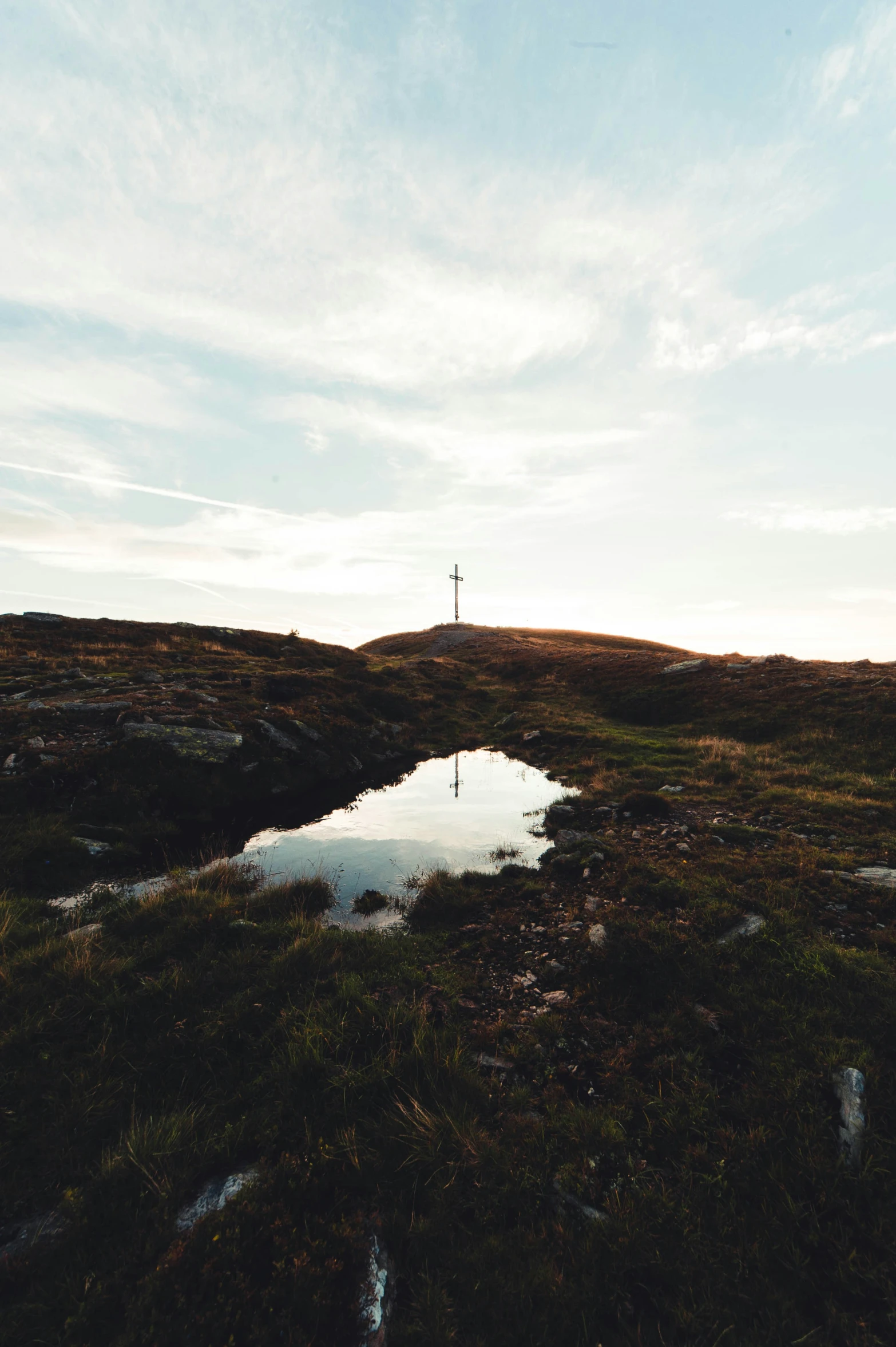 a man on the top of a hill holding an umbrella looking into the distance