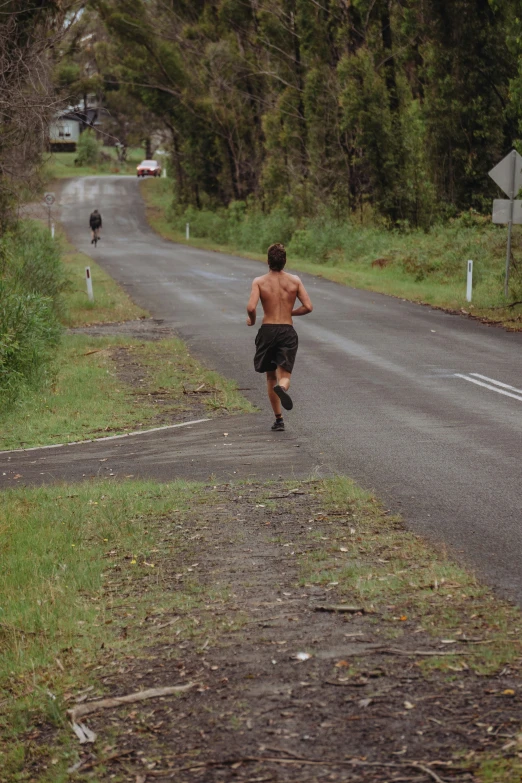 man running in road by woods and signs