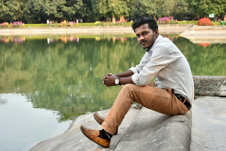 a man is sitting by the water with his feet crossed