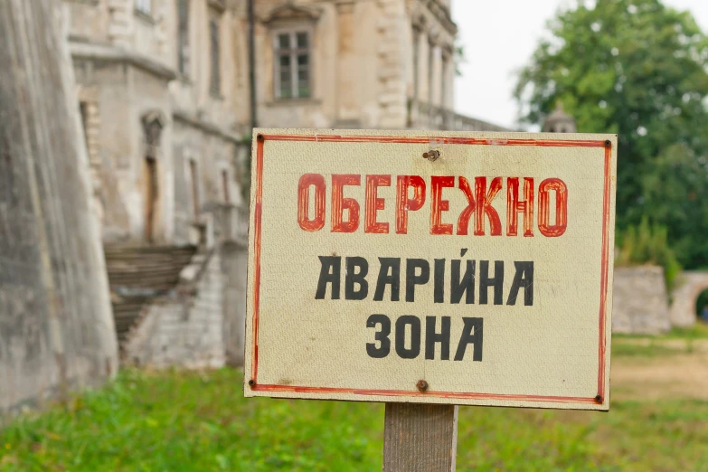 a sign with foreign writing next to some grass