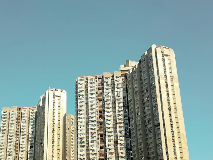 tall apartment buildings with balconies on the top and below in a clear blue sky