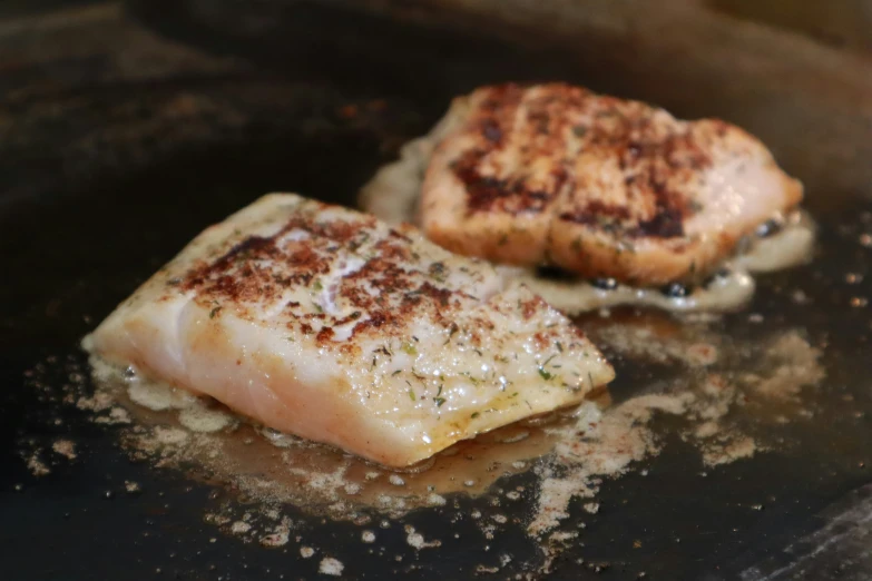 two fried fish patties in a frying pan