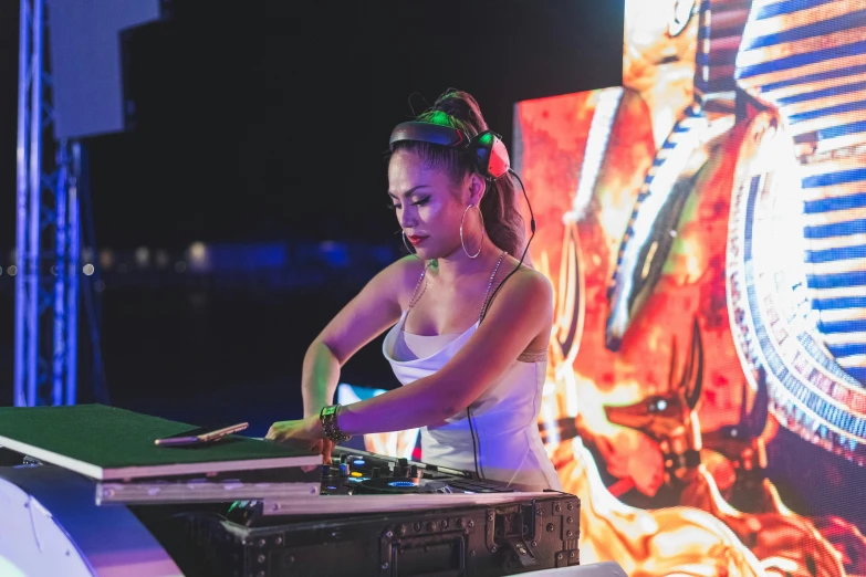 a woman in white dress with headphones on playing music at an event