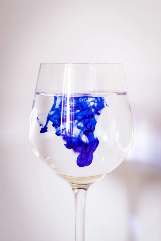 a wine glass filled with liquid that has blue and purple flowers in it