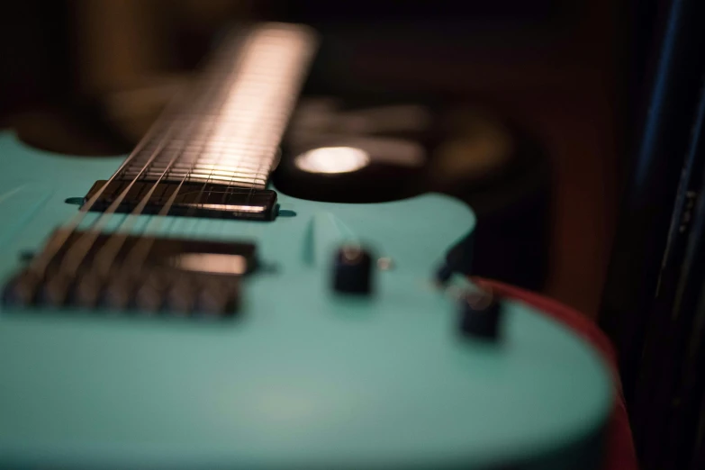 a turquoise guitar sits against a wooden background