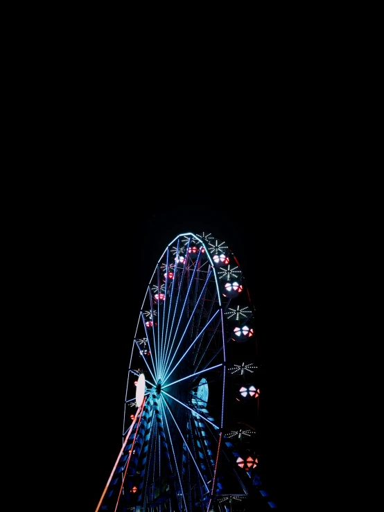a ferris wheel lit up at night by a building