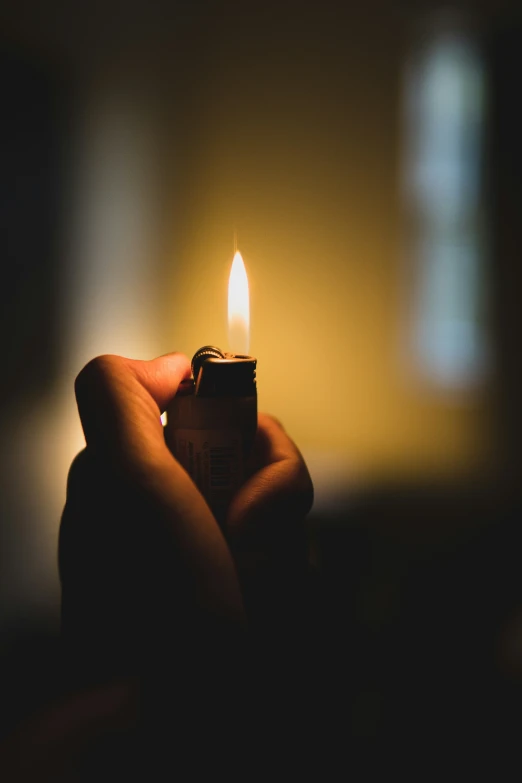 someone holds a lit candle inside the dark