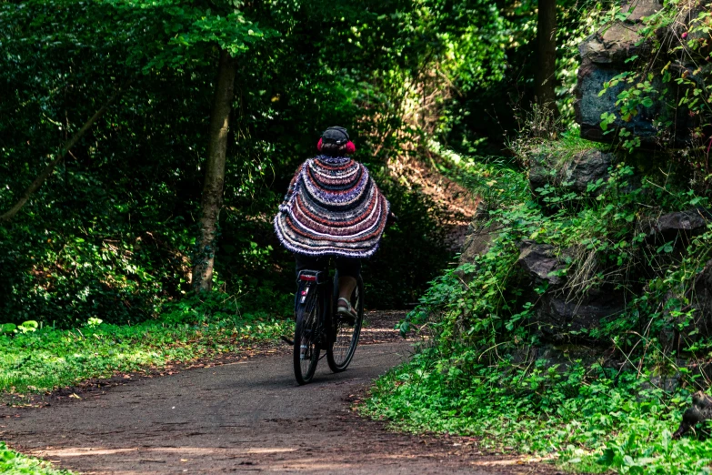 a person wearing a shawl riding their bicycle