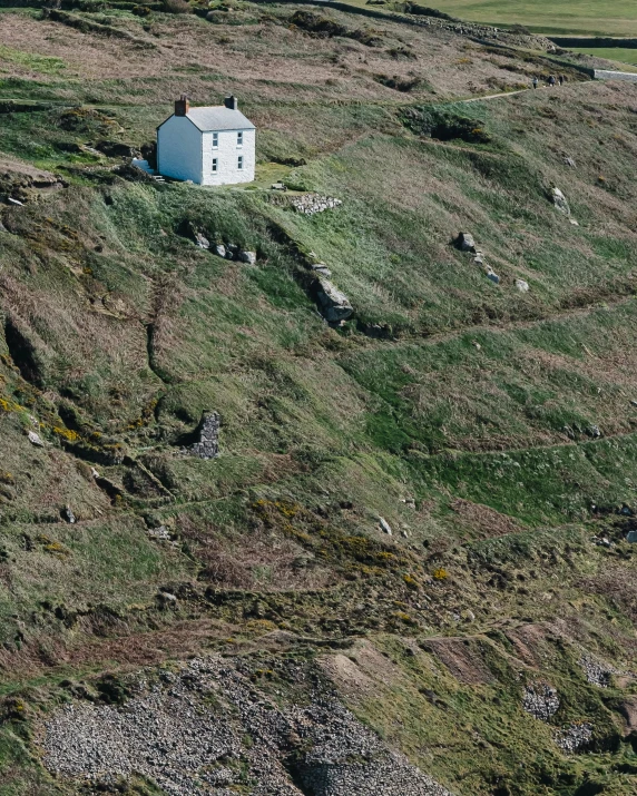 a house sits in the middle of a grassy hill