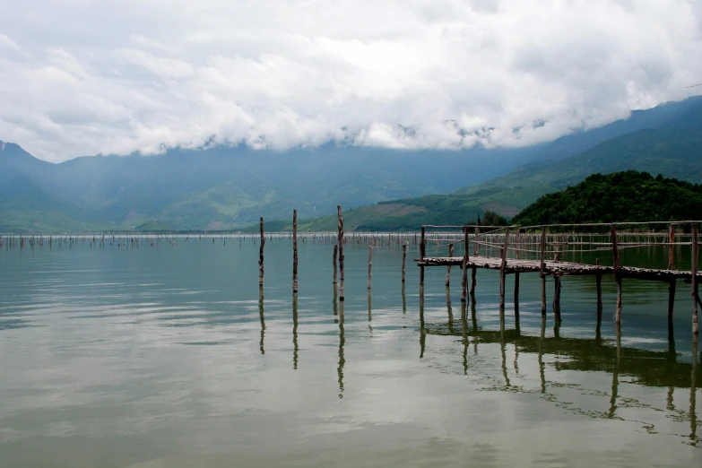 two rows of poles in the water in front of mountains