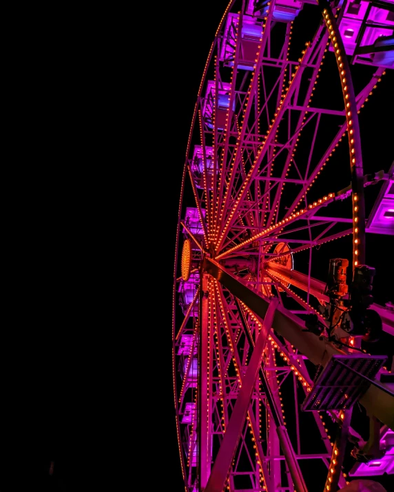 a ferris wheel at night, the lights glowing pink
