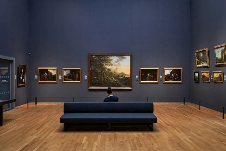 man sitting on a blue bench in an art gallery