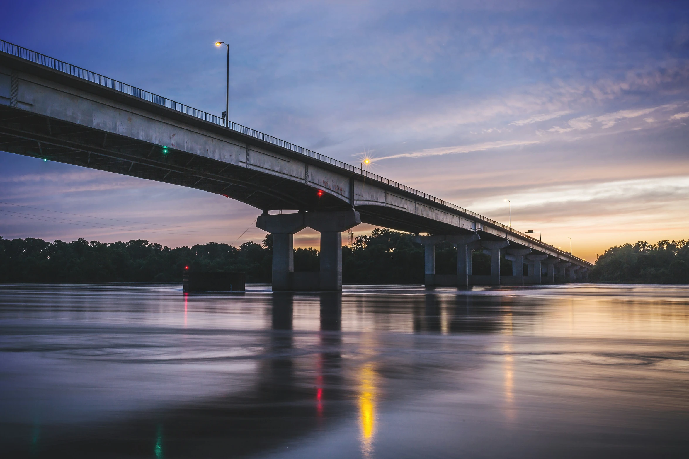 a train bridge crossing over the water at dusk