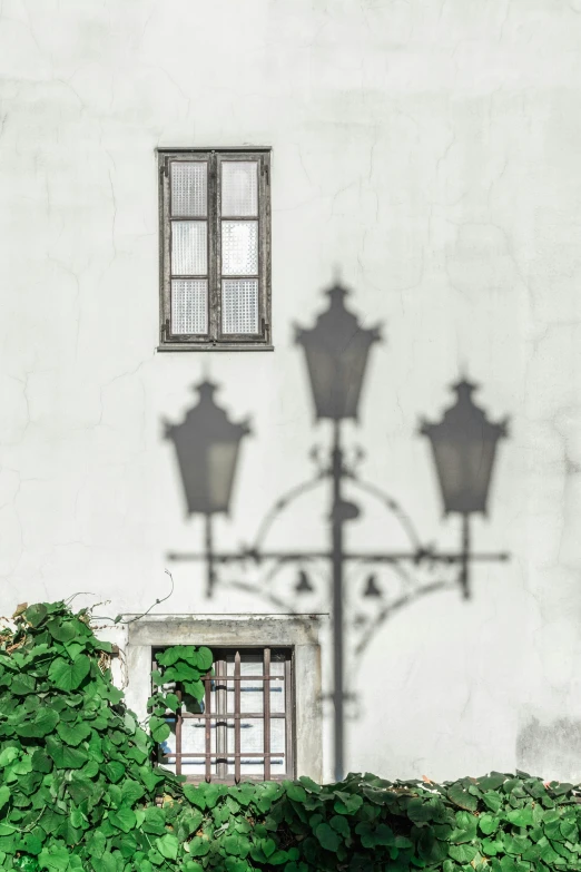 the wall is painted white with a lamp post and a shadow of a building