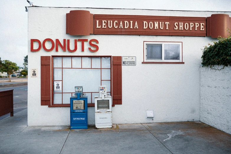 there is a donut shop with a fountain and telephone outside