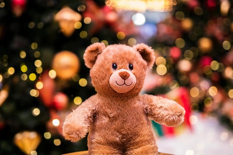 teddy bear sitting on display in front of the christmas tree