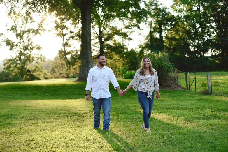 two people holding hands as they walk through the grass