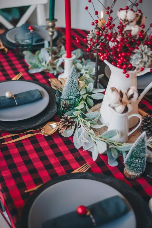 a table is decorated with christmas decor, plates, napkins and candles