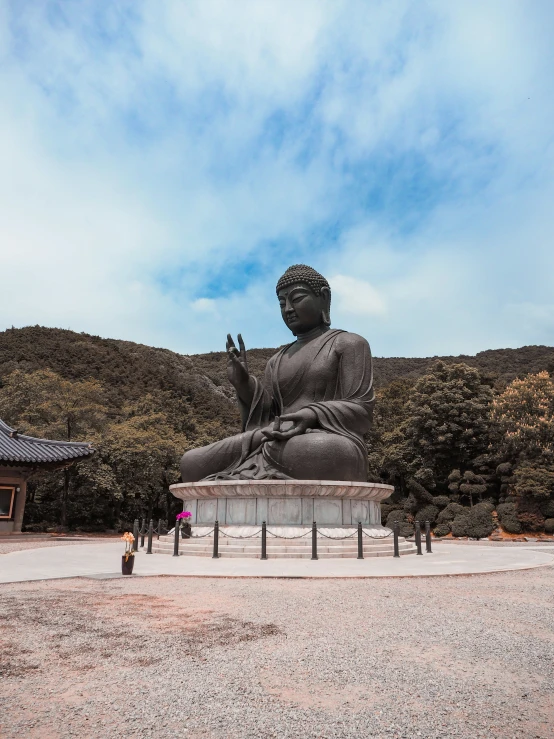 statue is seated on bench in courtyard with mountain behind