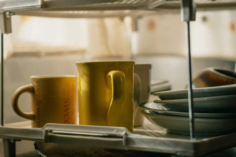 a couple of yellow coffee cups are sitting on a rack