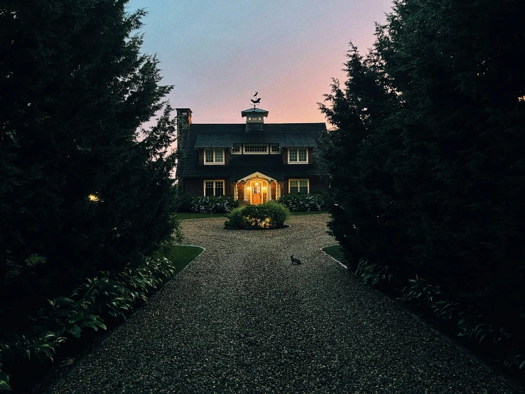 there is a house surrounded by trees and lit lights