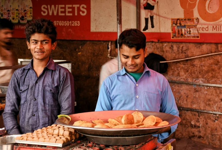 two men in a street near a store selling bread