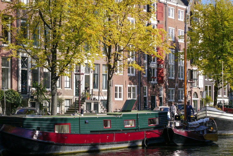 two boats floating down the river side in front of tall buildings