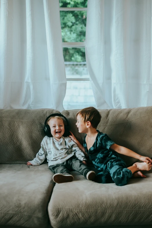 two young children sit on the couch laughing