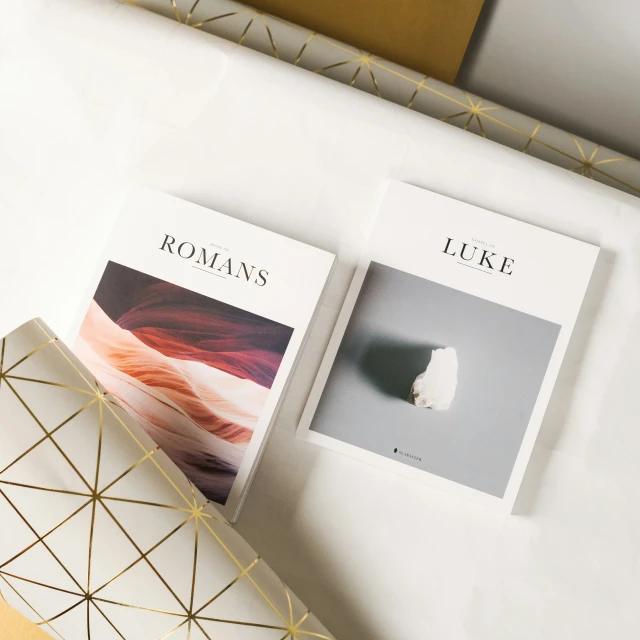 two white pamphlets sitting on top of a wooden desk