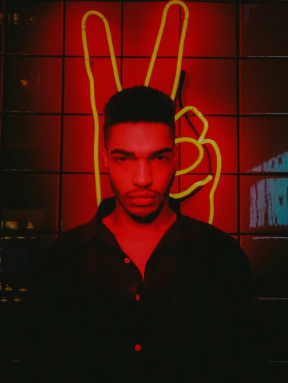 a man in black shirt standing by neon light