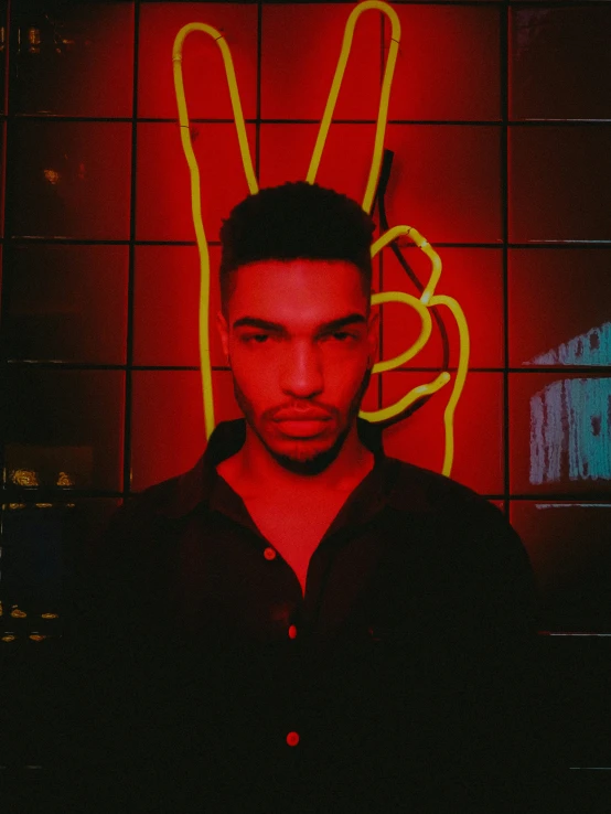 a man in black shirt standing by neon light