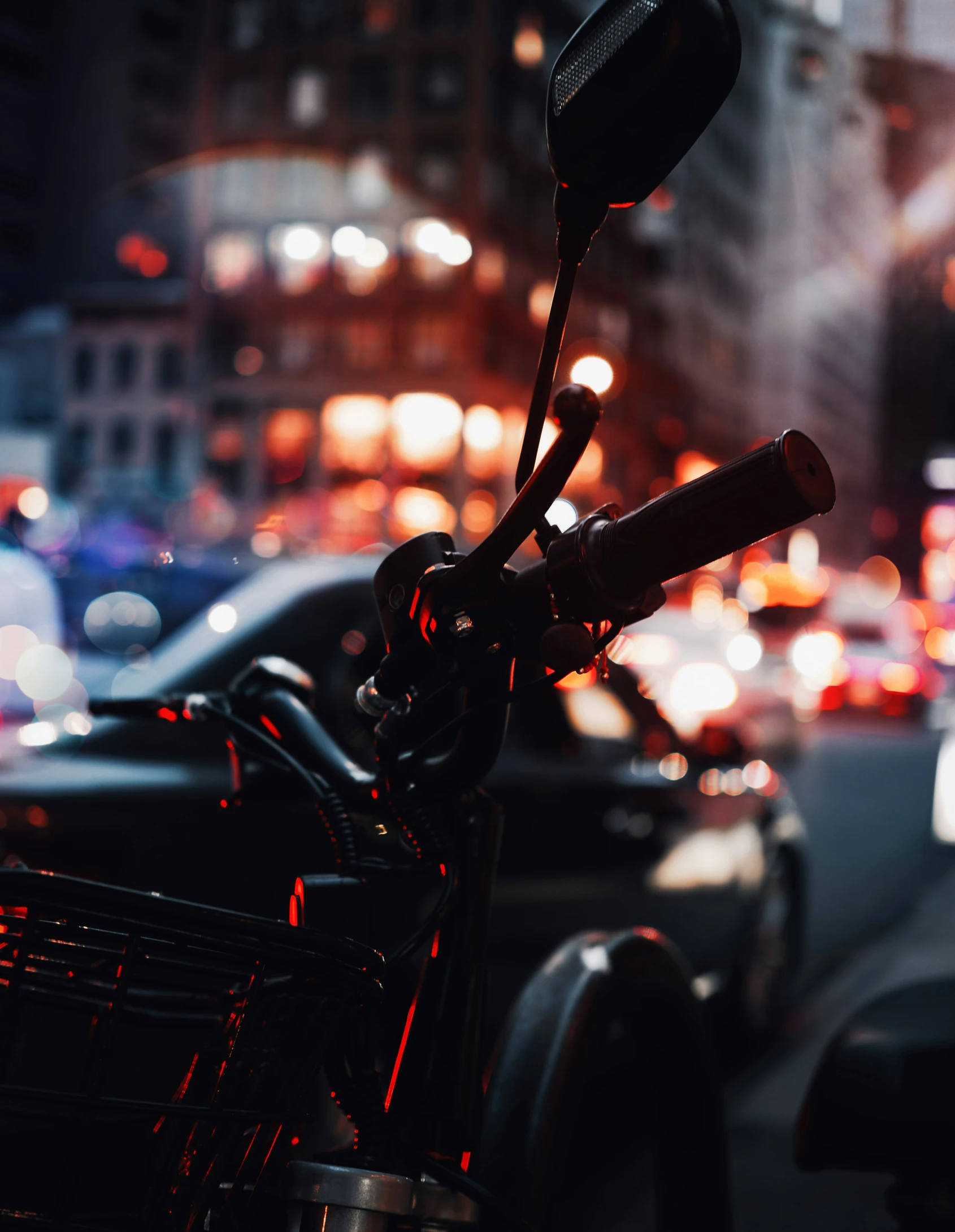 the view of a street at night through a motorcycle mirror