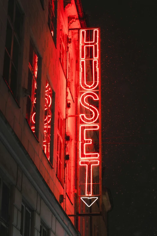 an illuminated red neon sign on the side of a building