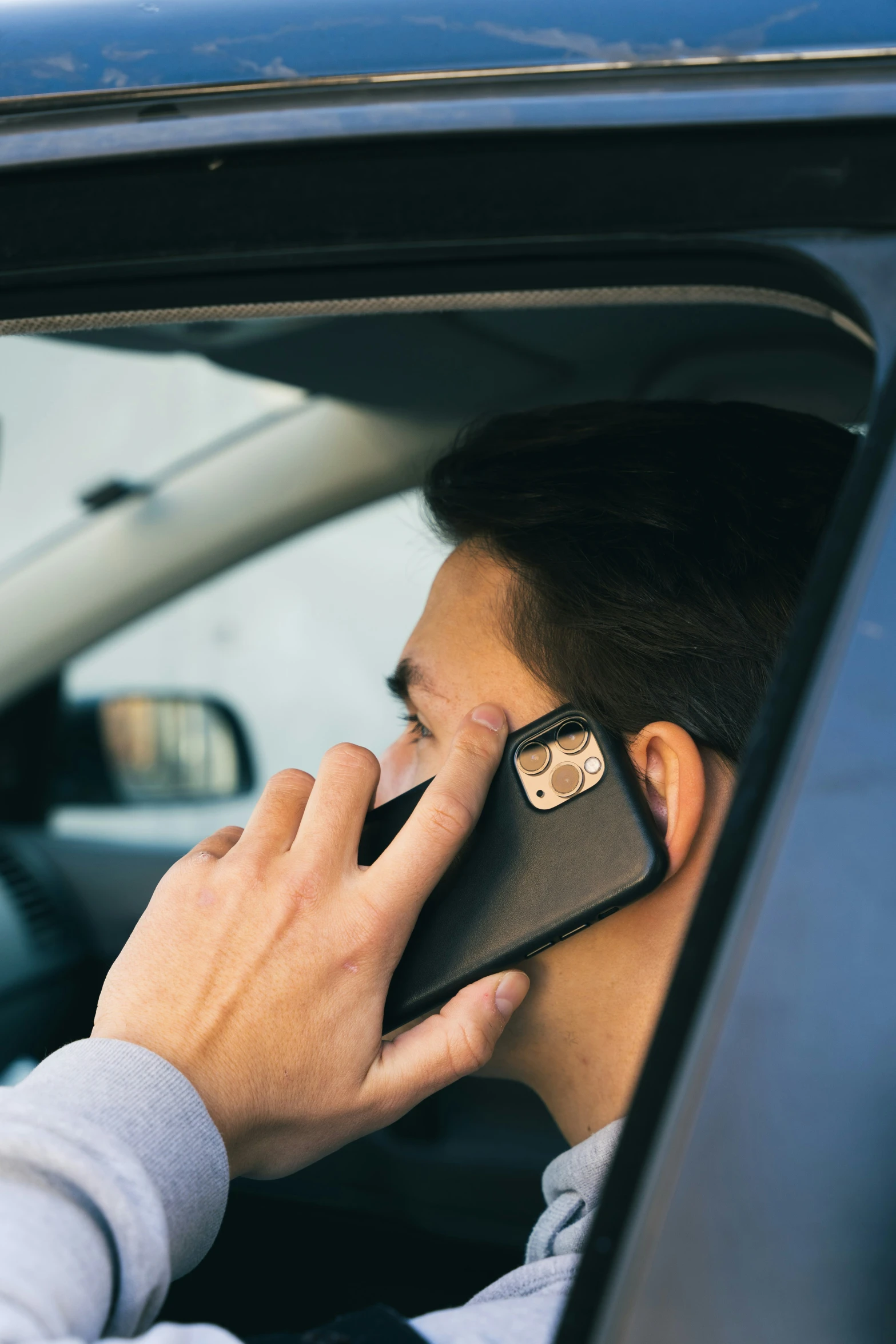 a man sitting in a car talking on a cell phone